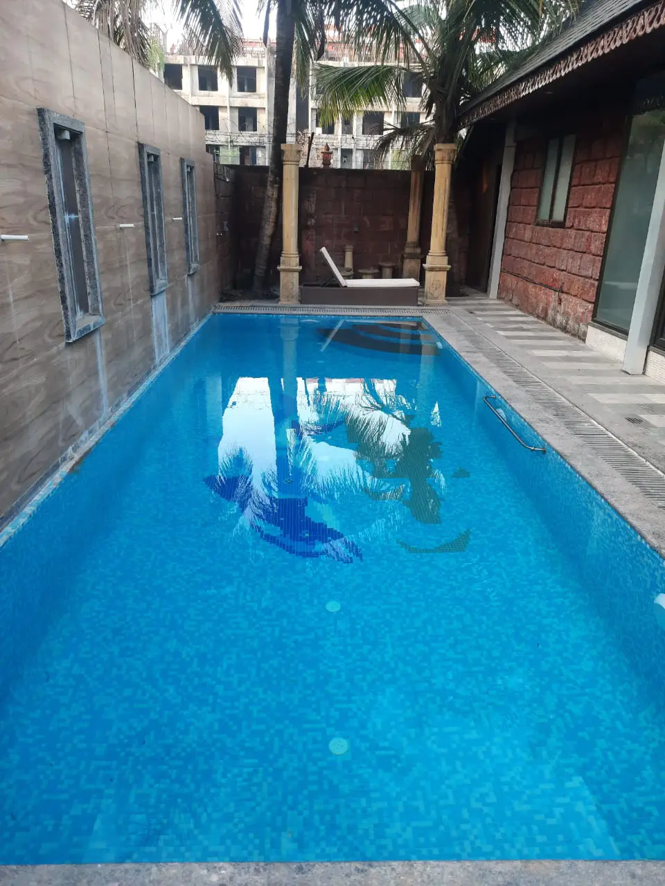 Compact residential swimming pool with tiled wall and deck area
